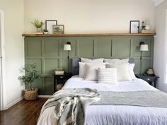 a bed with white linens and pillows in a bedroom next to a wooden headboard