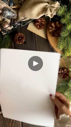 someone is holding up a laptop computer in front of christmas decorations and pine cones on the table