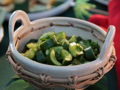 a white bowl filled with green vegetables on top of a table next to other plates