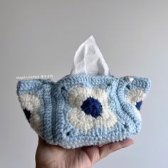 a hand holding a blue and white crocheted bag with an eye on it