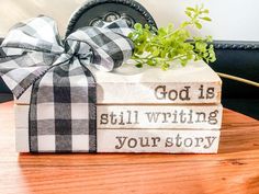 a gift wrapped in plaid ribbon sitting on top of a wooden table next to a potted plant