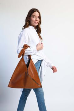 FEATURES Meet Remy. A modern take on the classic Japanese hobo tote. Designed with ease in mind. Slouchy, slightly oversized bag with plenty of storage for your on-the-go essentials. This bag features soft leather with a knotted adjustable strap that can be worn over the shoulder or as a crossbody. Perfect bag for work and travel. SIZE Measurements: 17" W x 11.5" H x 1" D, adjustable strap drop 11.5" at longest MATERIAL 100% top grain leather with double-sided locking metal zipper detail DETAILS Modern Rectangular Hobo Bag For Fall, Modern Bags With Leather Handles For Fall, Modern Cognac Satchel Hobo Bag, Versatile Hobo Bag With Zipper Closure For Shopping, Modern Hobo Bag With Leather Handles For Errands, Modern Cognac Hobo Bag With Removable Pouch, Modern Hobo Satchel Bag For Errands, Modern Cognac Shoulder Bag For Fall, Modern Hobo Bag For Errands