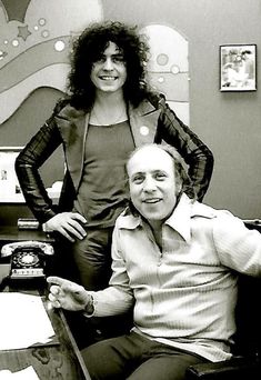 a man sitting next to a woman on top of a chair at a desk in an office