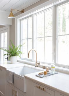 a kitchen with white counter tops and gold faucets on the window sill