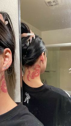 a woman with tattoos on her neck is looking at herself in the mirror