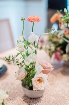 flowers in a vase sitting on top of a lace tablecloth covered dining room table