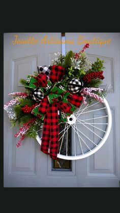 a bicycle wheel wreath with red and black plaid ribbon on the front door for christmas