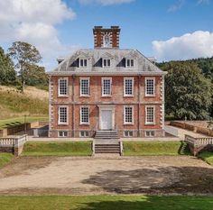 an old red brick house with two chimneys on the roof and stairs leading up to it