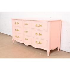 a pink dresser with gold handles and drawers