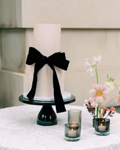 a white and black wedding cake on a table with flowers in vases next to it