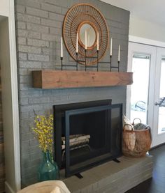 the fireplace is painted gray and has candles on it, along with a basket full of flowers