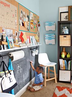 a young boy sitting on the floor in front of a chalkboard