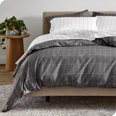 a bed with grey and white comforter in a bedroom next to a wooden table