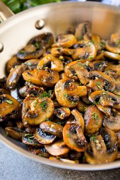 a pan filled with mushrooms and parsley on top of a table