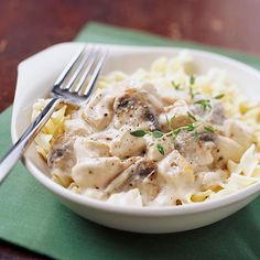 a white bowl filled with pasta covered in gravy on top of a green napkin