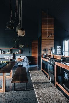 a kitchen with black walls and wooden cabinets, an island table and chairs in the middle