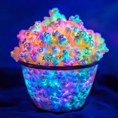 a bowl filled with colorful gummy bears sitting on top of a blue tablecloth