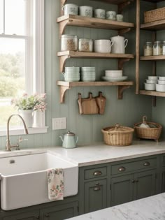 a kitchen with green cabinets and shelves filled with dishes