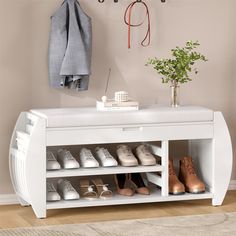 a white shoe rack with shoes on it next to a potted plant and coat rack