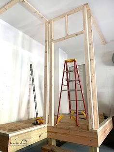 an unfinished room with ladders and work bench in the foreground, next to a wall that is being built