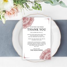 a white plate topped with a thank card next to a bouquet of flowers and greenery