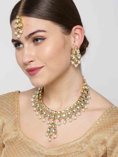 This stunning jewelry set consists of a classic drop necklace, a maang tikka, and a pair of matching drop earrings. The gold toned & off-white pearl necklace with a central drop shown here comes with kundan stone studs & beads, is gold-plated, and secured with an adjustable drawstring closure. A pair of matching drop earrings come secured with a post and back closure. This beautiful statement piece can add impact to any outfit for any festive occasion! Product color may vary based on the monitor Kundan Chandbali Jewelry Set With Pearl Drop, Pearl Drop Chandbali Jewelry Sets For Diwali, Chandbali Pearl Drop Bridal Necklace For Diwali, Festive Kundan Chandbali Necklace With Pearl Drop, Bollywood Style Festive Jewelry With Pearl Drop, Bollywood Style Pearl Drop Jewelry For Festive Occasions, Festive Bollywood Jewelry With Pearl Drop, Bollywood Kundan Bridal Necklace With Pearl Drop, Kundan Chandbali Necklace With Pearl Drop