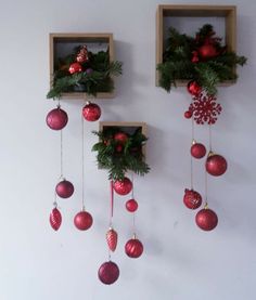 two wooden boxes with christmas ornaments hanging from them, one is filled with greenery and the other has red baubs