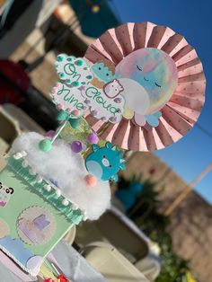 a pink and blue cake with an animal topper on it's head, sitting in front of a building