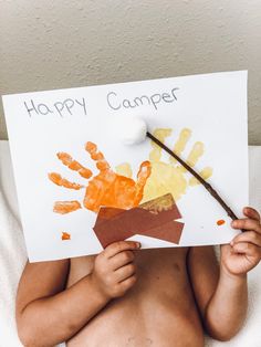 a baby holding up a sign that says happy camper