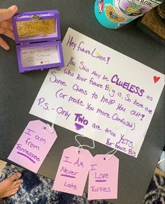 a child's handwritten note and two tags on a table with other items