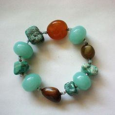 This unique bracelet has several different polished stones, each separated by tiny silver tone beads in a stretch bracelet.  There are turquoise, carnelian, and jade pieces in this bracelet.  Both the carnelian and jade pieces are known for their healing powers.  The stones are approximately ¾ inch each in width and the bracelet is 8 inches in length without stretching it.  It is in excellent condition. Thanks for looking and visiting my shop. Jewelry items may be combined for shipping discounts. Please view the shop often as I regularly add new and interesting items and offers are always considered. Golden Co, Shop Jewelry, Unique Bracelets, Healing Powers, Stretch Bracelet, Stretch Bracelets, Arm Band, Stretching, 4 Inch