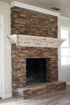 an empty room with a stone fireplace in it