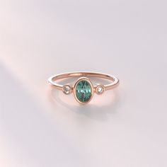 a gold ring with a green stone and three white stones on the side, sitting on a plain surface