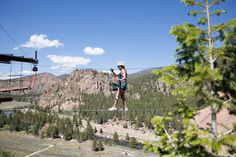 a man is zipping through the air on a rope line above trees and mountains