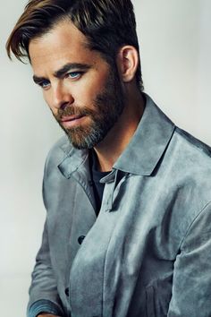 a man with a beard and blue eyes wearing a gray shirt looking at the camera