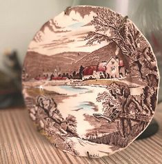 a brown and white plate sitting on top of a table next to a glass vase