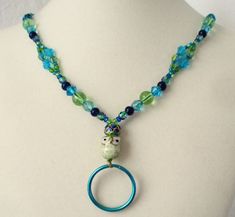 This blue flower beaded lanyard can be used as a badge holder, an I.D. holder, or keychain necklace - it's a multi-use accessory for home or office! 32" in length, long enough to put on or remove overhead. It also has an easy-to-use metal lobster clasp for your conveniece. It's made with blue and green glass beads, a green ceramic owl bead, and strung on strong C-Lon beading cord. Snap-on badge holder, clip, and keyring are included to keep your badges or keys ready when you need them. This blue Adjustable Beaded Blue Lanyards, Adjustable Blue Beaded Lanyards, Handmade Blue Lanyards For Gifts, Handmade Blue Lanyard As Gift, Handmade Blue Lanyards As Gifts, Keychain Necklace, Beaded Lanyard, Beading Cord, Beaded Lanyards