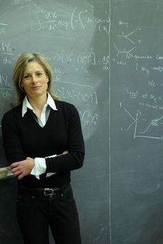 a woman standing in front of a blackboard with writing on it