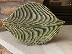 a green leaf shaped object sitting on top of a counter next to a brick wall