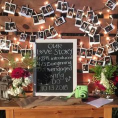 a wooden table topped with pictures and flowers next to a chalkboard that says our love story