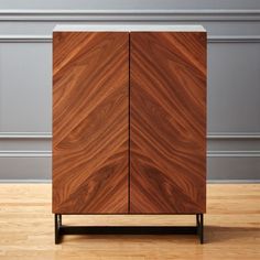 a wooden cabinet sitting on top of a hard wood floor next to a gray wall