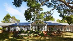 a white house sitting on top of a lush green field next to trees and bushes