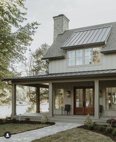 a house with a porch and covered in metal roofing on the front lawn area