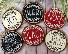 four decorated christmas cookies sitting on top of a wooden table next to pine cones and evergreen branches