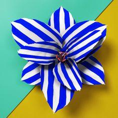 a blue and white paper flower on top of a yellow and green striped wallpaper