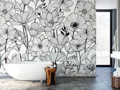 a white bath tub sitting next to a wall with flowers painted on it's side