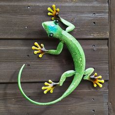 a green and yellow lizard sitting on top of a wooden wall