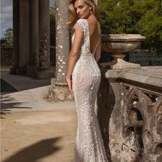 a woman in a white wedding dress standing on a stone wall with columns and pillars behind her