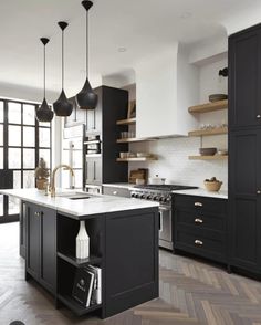 a large kitchen with black cabinets and white counter tops, an island in the middle