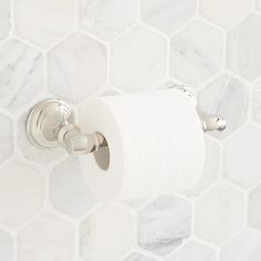 a roll of toilet paper is hanging on the wall next to a white marble tile